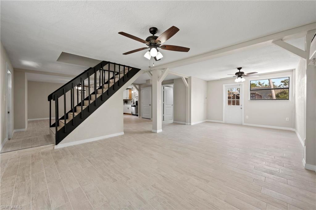 17397 Lee Road Fort Myers, FL 33967 - Photo 6 of 22 a view of an empty room with chandelier fan and wooden floor