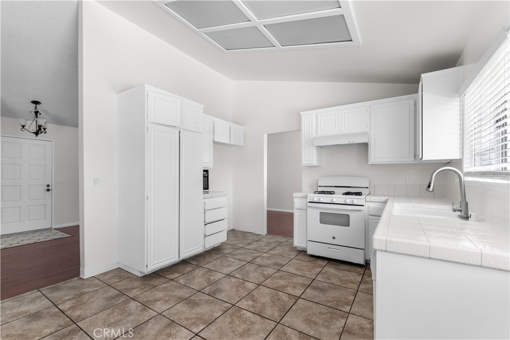1232 Kings Road Palmdale, CA 93551 - Photo 20 of 32 a kitchen with a stove a sink and a refrigerator