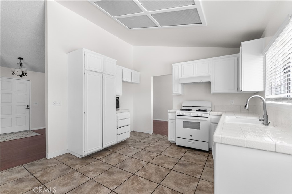 1232 Kings Road Palmdale, CA 93551 - Photo 25 of 32 a kitchen with a stove a sink and a refrigerator