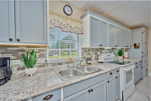 a kitchen with granite countertop a sink a stove and cabinets
