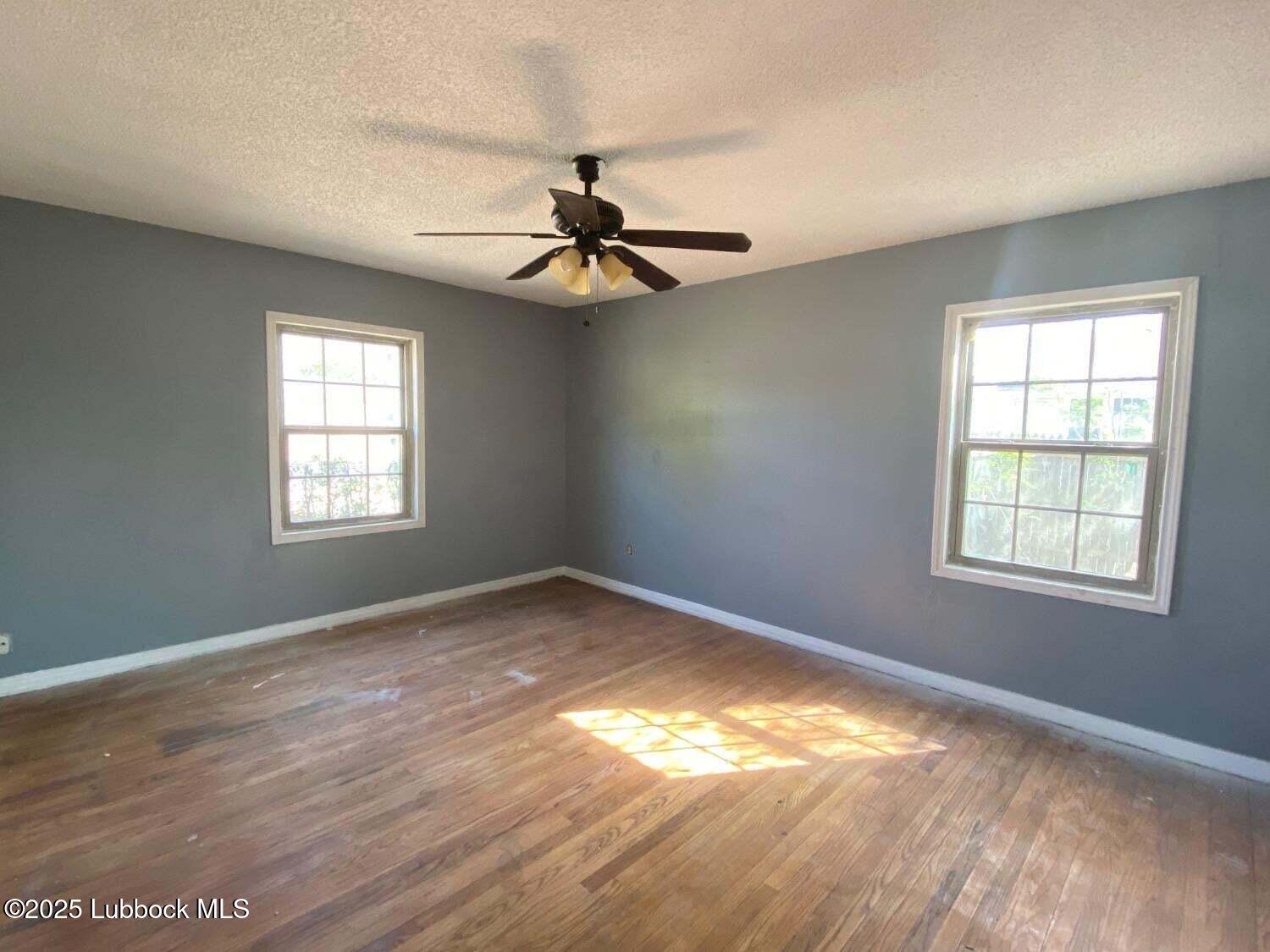 1917 39th Street Lubbock, TX 79412 - Photo 2 of 7 an empty room with windows and fan