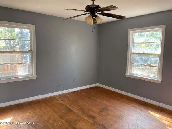 an empty room with a window and a fan