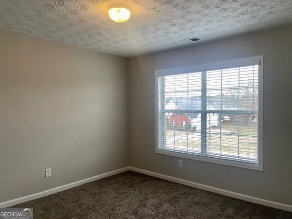 an empty room with chandelier fan and windows