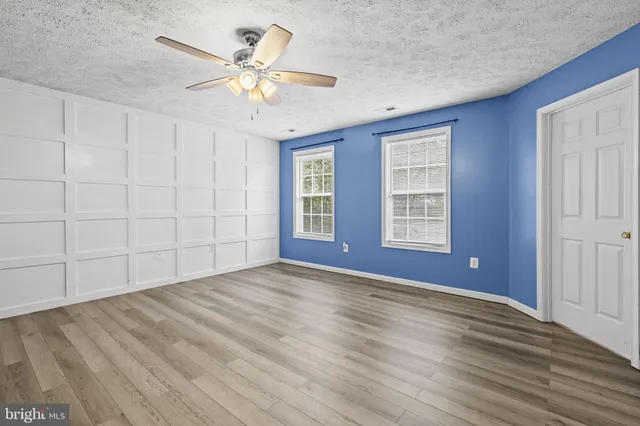 a view of an empty room with window and chandelier fan