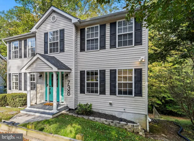 a view of a house with a yard and large tree