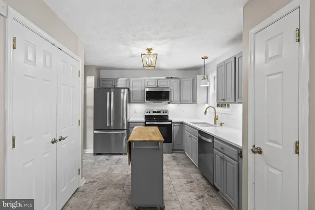a large kitchen with a sink stainless steel appliances and cabinets
