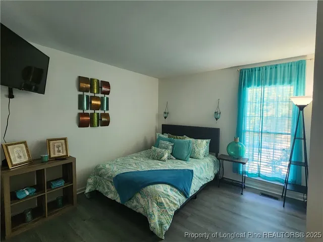 a bedroom with a bed a flat screen tv and guitar