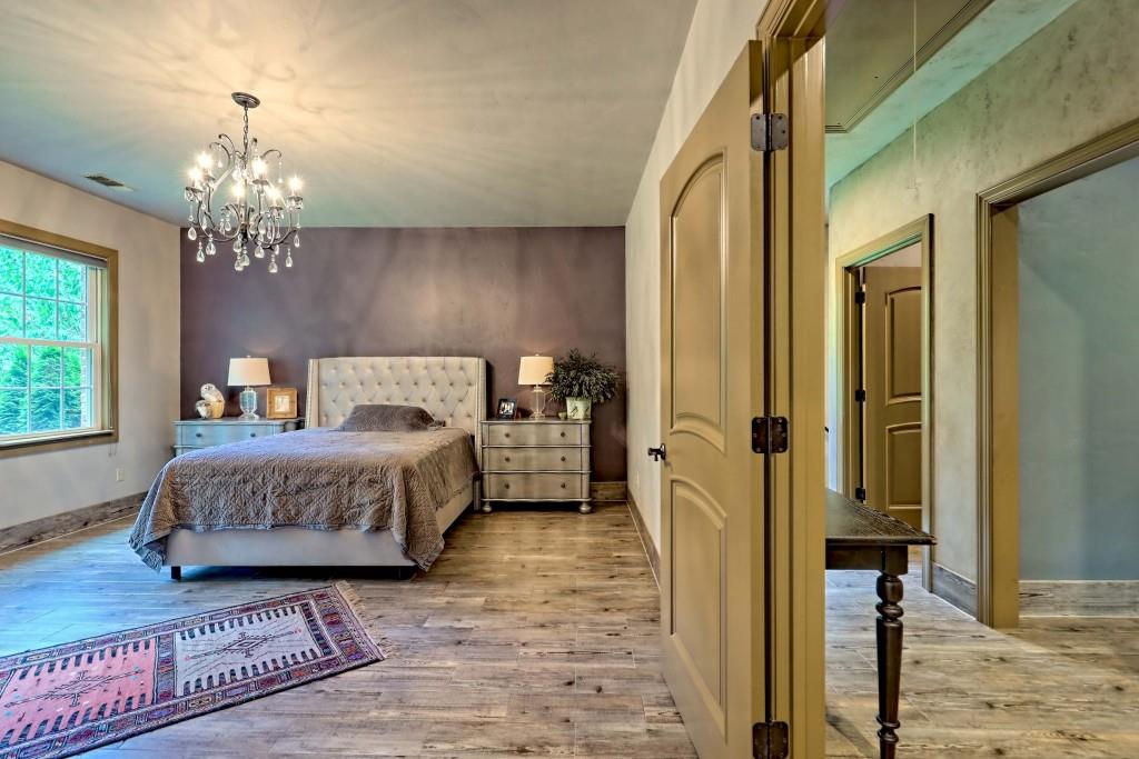 1422 Wolffork Road Rabun Gap, GA 30568 - Photo 46 of 78 a spacious bedroom with a bed chandelier and a window