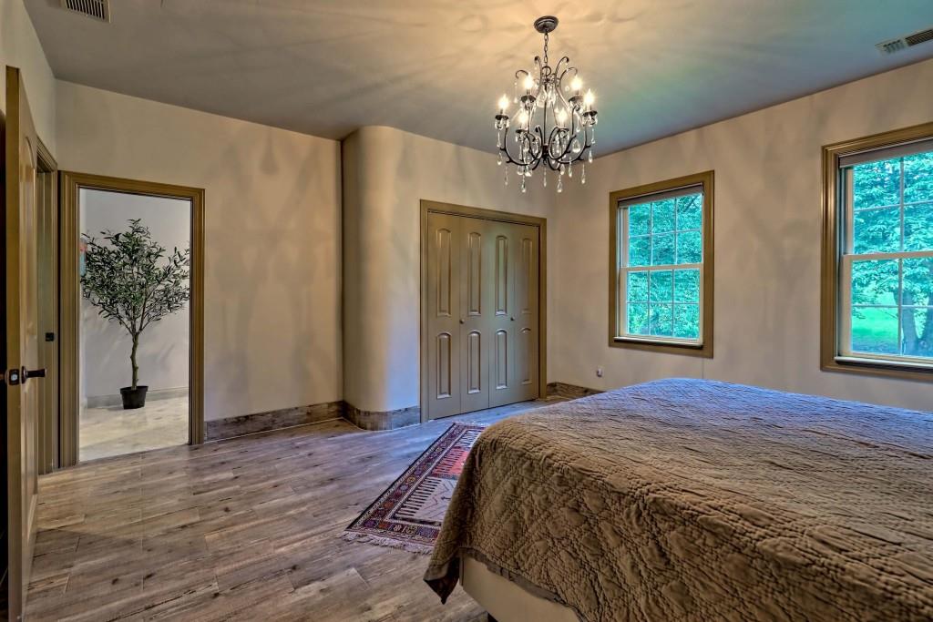 1422 Wolffork Road Rabun Gap, GA 30568 - Photo 47 of 78 a spacious bedroom with a balcony a bed and a chandelier