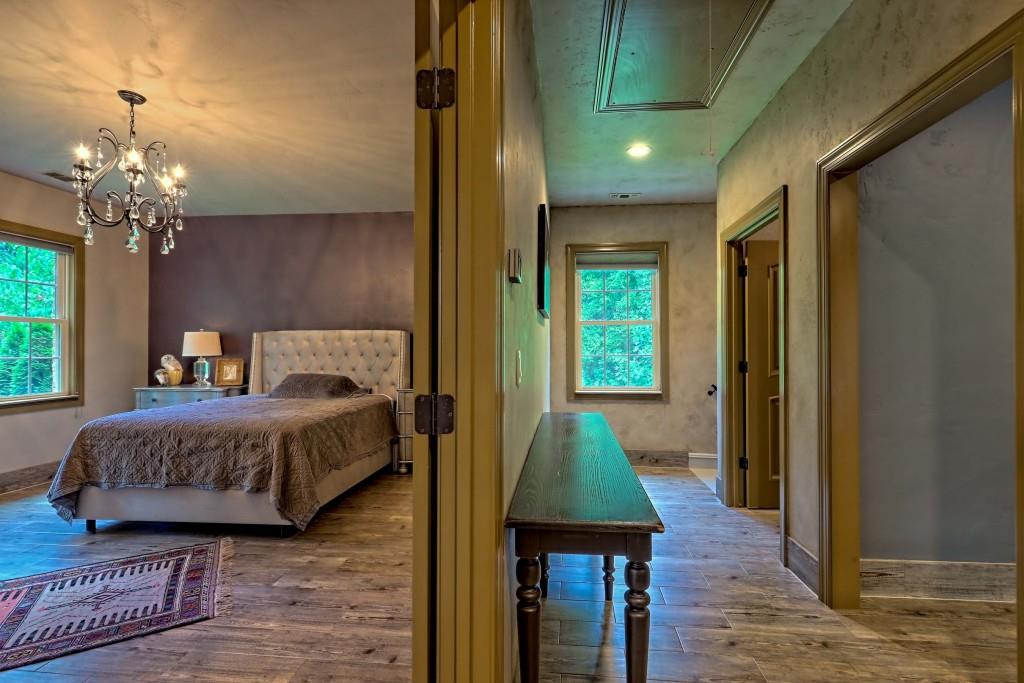 1422 Wolffork Road Rabun Gap, GA 30568 - Photo 48 of 78 a spacious bedroom with a bed and a chandelier