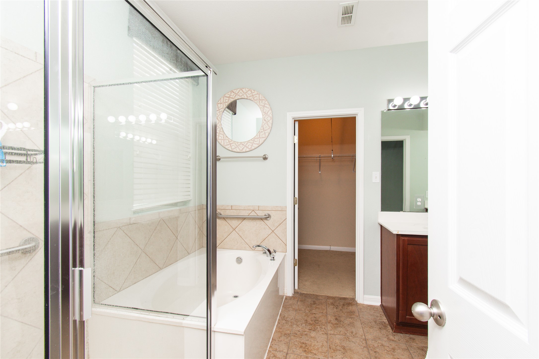 421 Shadow Point San Marcos, TX 78666 - Photo 13 of 24 Bathroom with vanity, a spacious closet, a garden tub, a stall shower, and light tile patterned floors