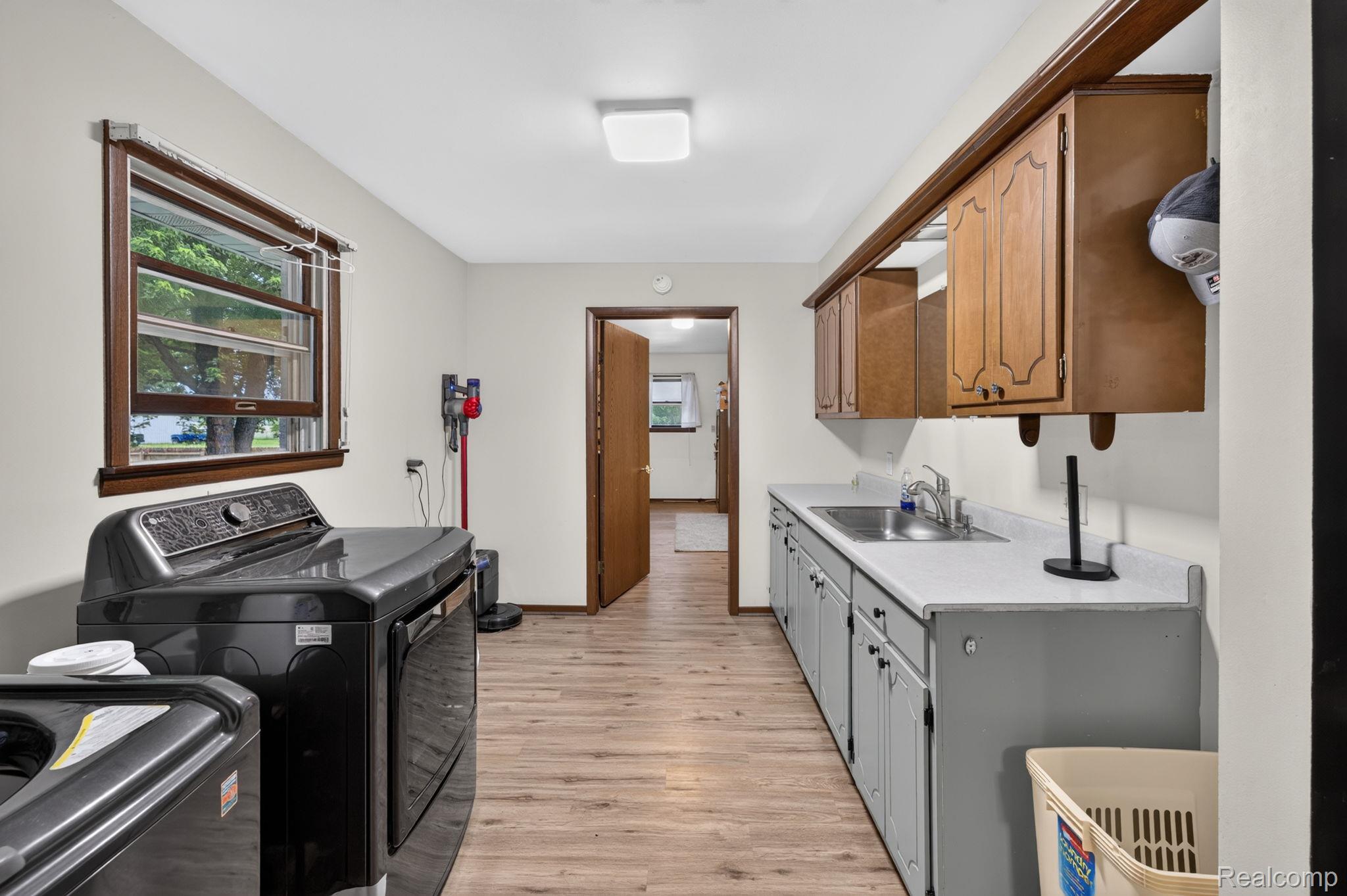 5330 Sheridan Road Saginaw, MI 48601 - Photo 22 of 50 Dedicated utility space with wood-finish flooring, a window with wood trim, a built-in sink, and upper and lower cabinetry
