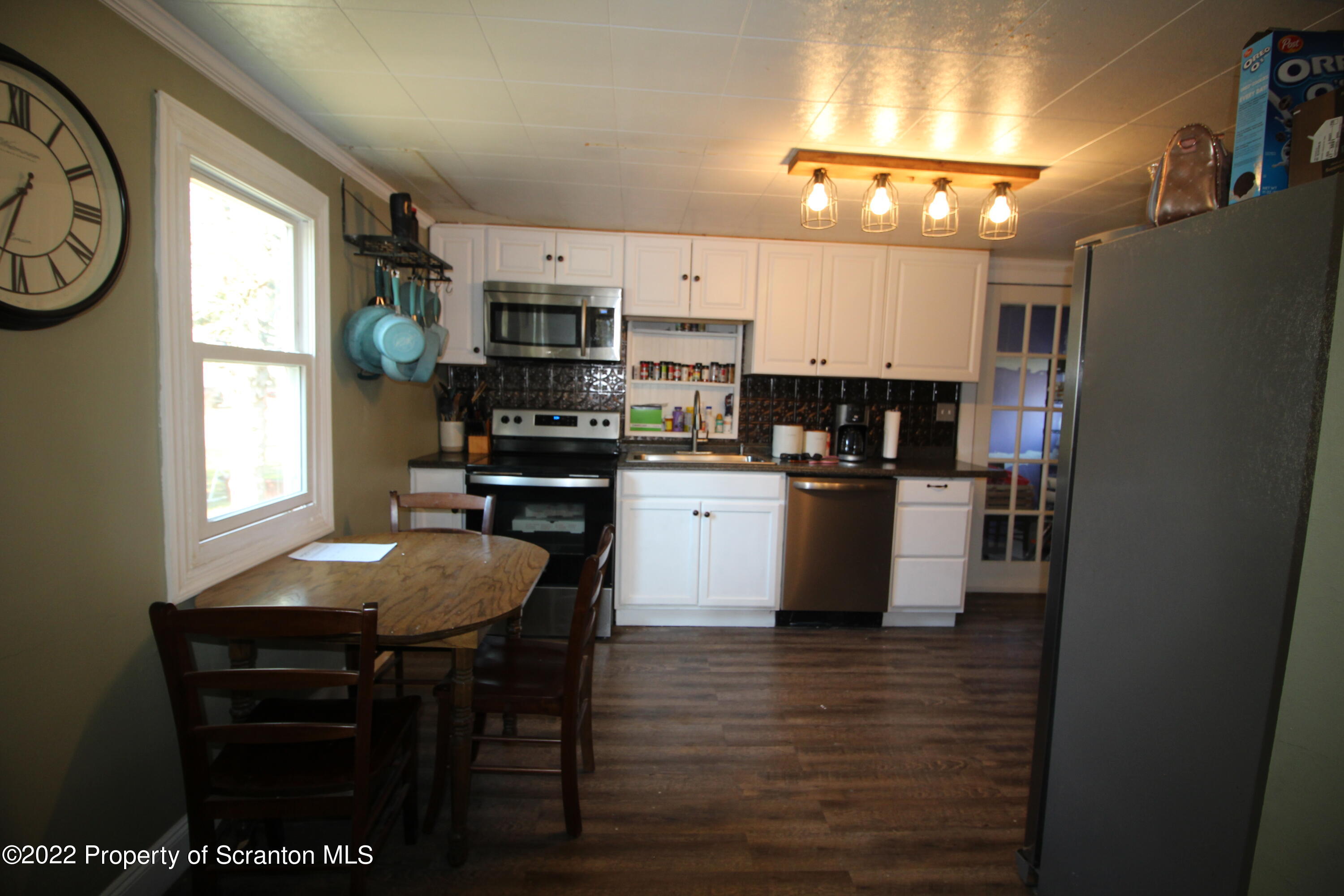 4001 Quicktown Road Moscow, PA 18444 - Photo 6 of 24 a kitchen with stainless steel appliances granite countertop a stove a refrigerator a sink a dining table and chairs with wooden floor