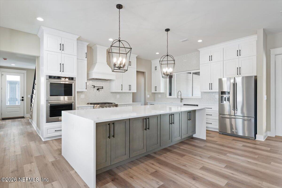 34883 Steeple Chase Way Callahan, FL 32011 - Photo 14 of 88 a large kitchen with stainless steel appliances kitchen island granite countertop a refrigerator a sink dishwasher a stove and white cabinets with wooden floor