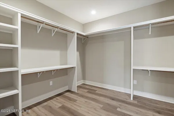 an empty room with wooden floor ceiling fan and windows