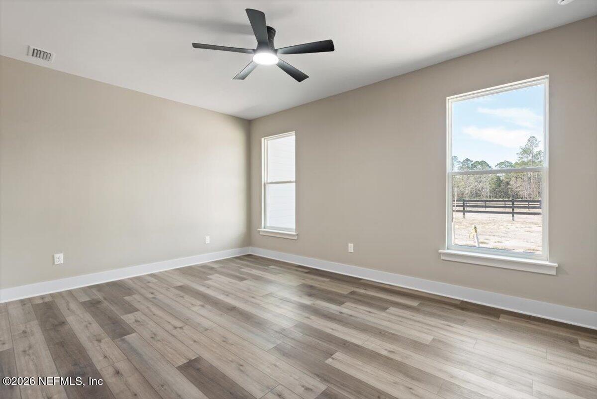 34883 Steeple Chase Way Callahan, FL 32011 - Photo 43 of 88 an empty room with wooden floor ceiling fan and windows