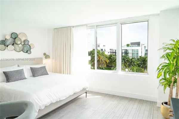 a bedroom with a large bed and a potted plant