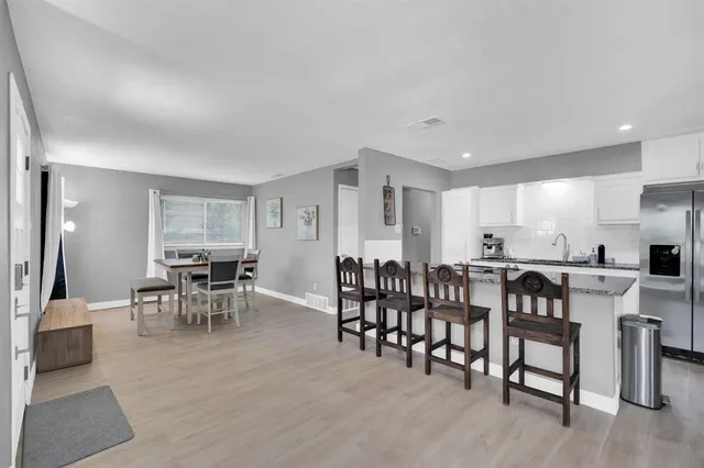 a view of dining room and livingroom with furniture wooden floor a rug a painting and a chandelier
