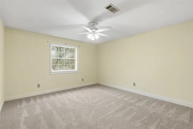 an empty room with a window and a fan