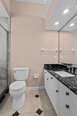 a bathroom with a granite countertop toilet a sink and a mirror