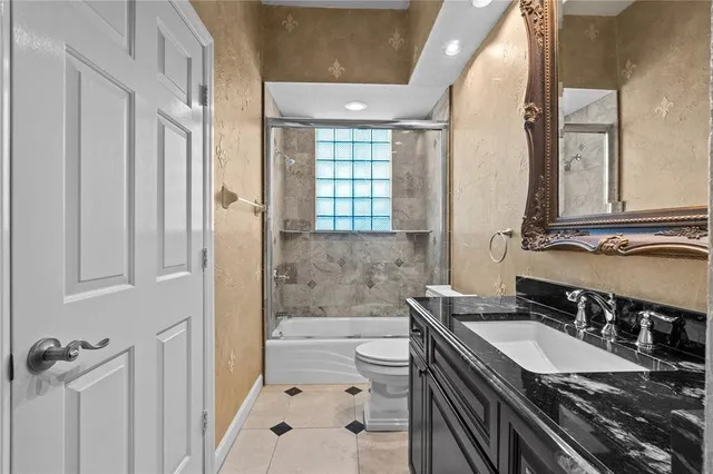 a bathroom with a granite countertop sink a toilet a mirror and shower