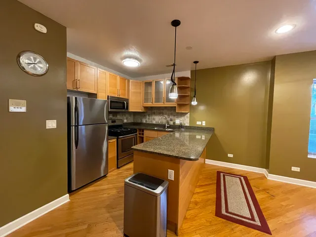 a kitchen with stainless steel appliances granite countertop a refrigerator a sink and a stove