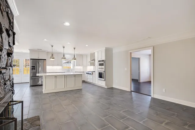 a kitchen with stainless steel appliances kitchen island granite countertop a refrigerator a oven a sink and white cabinets