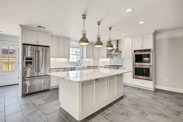 a large kitchen with white cabinets and stainless steel appliances