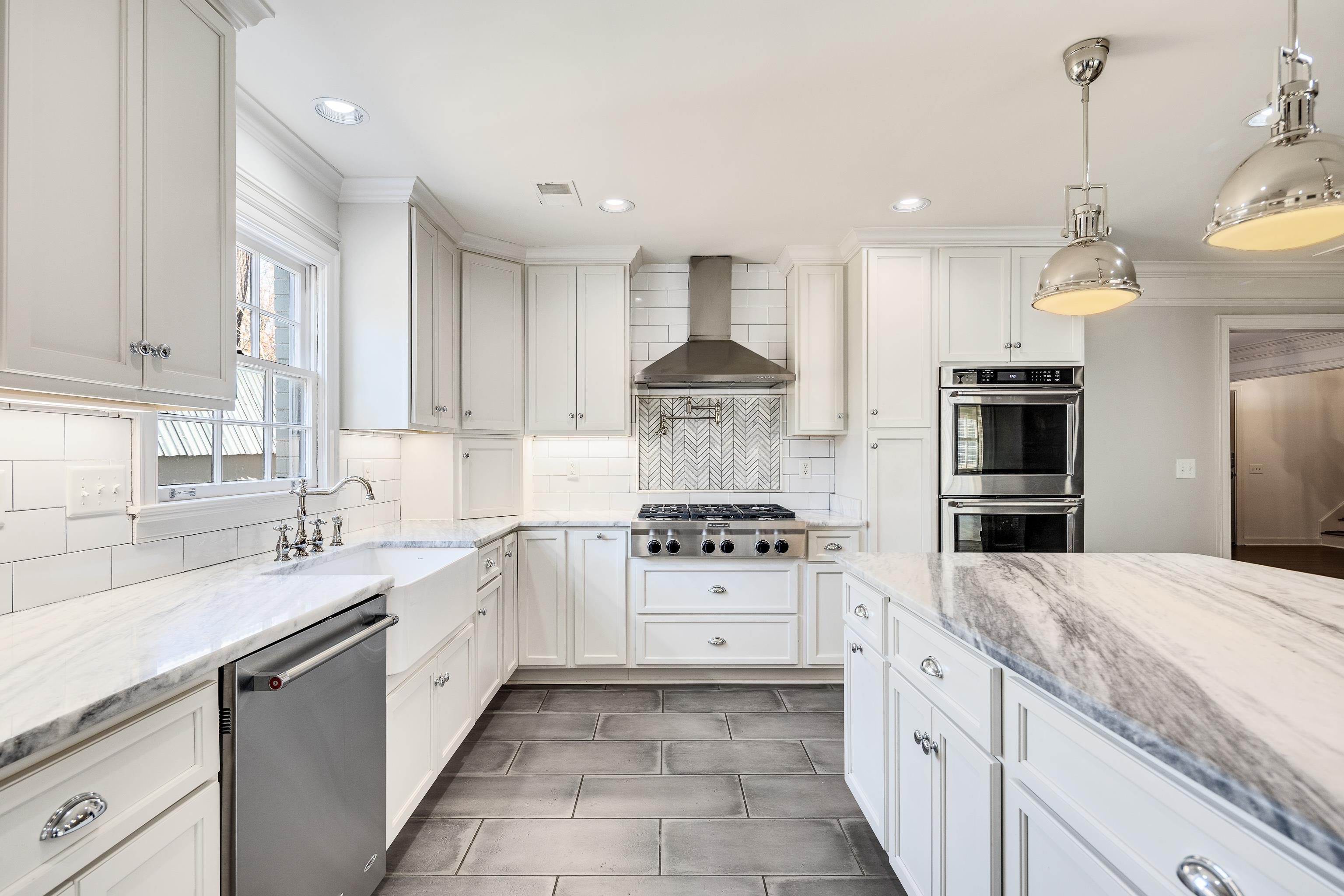 6867 River Birch Road Memphis, TN 38119 - Photo 14 of 40 Kitchen with light stone counters, white cabinets, stainless steel appliances, wall chimney range hood, and hanging light fixtures