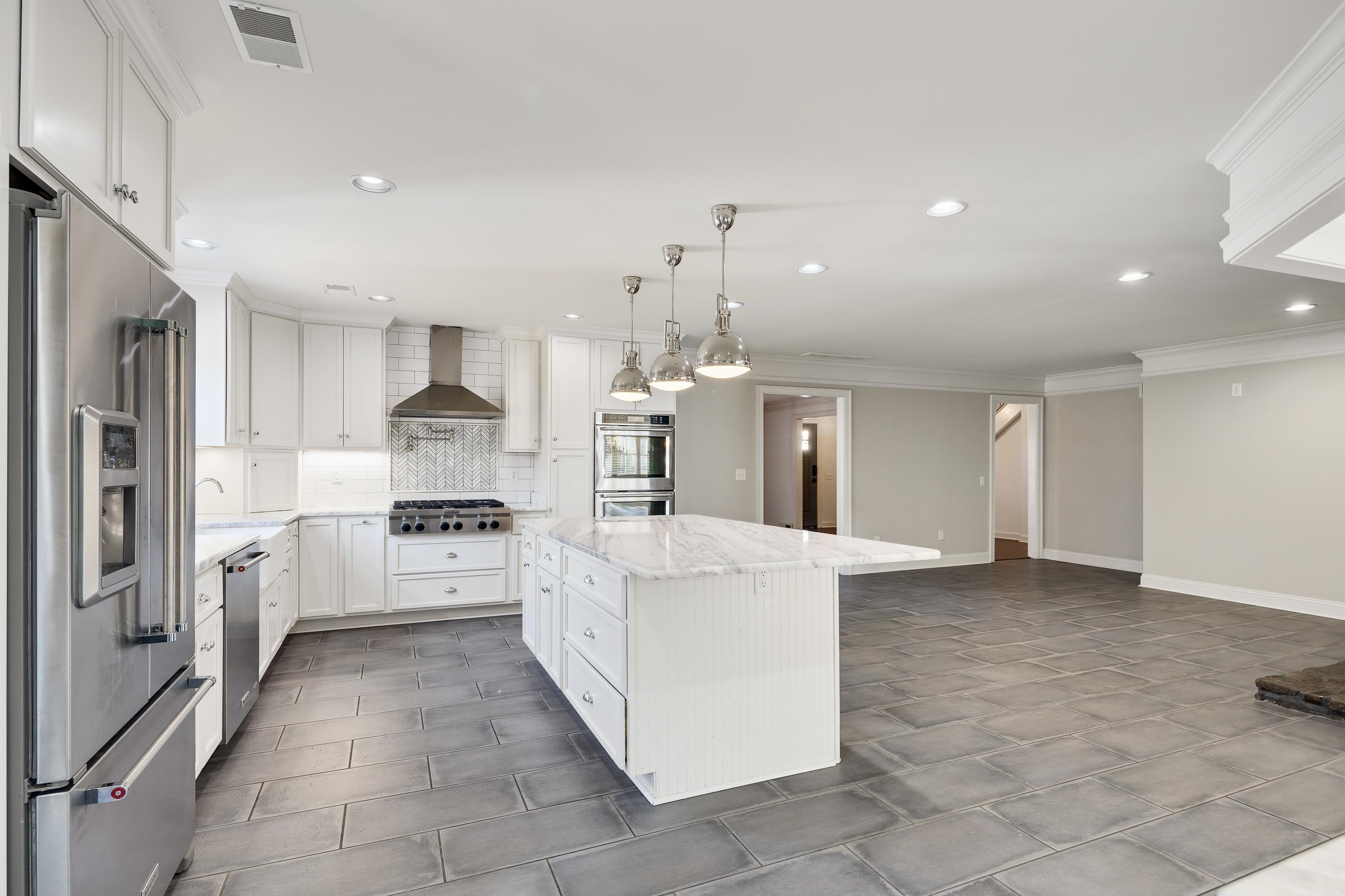 6867 River Birch Road Memphis, TN 38119 - Photo 18 of 40 Kitchen featuring appliances with stainless steel finishes, white cabinets, a center island, light stone countertops, and decorative light fixtures