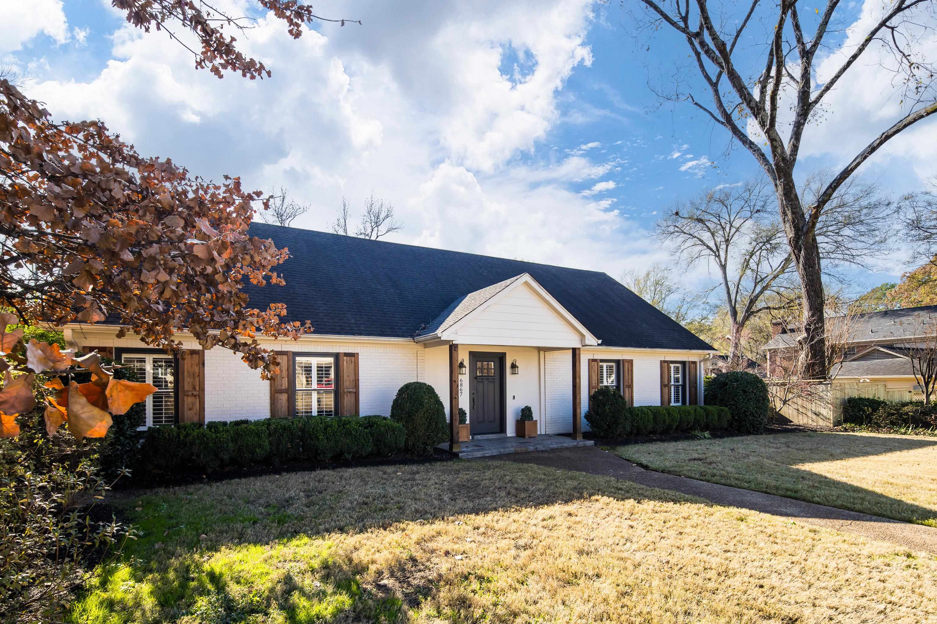 View of front of property with brick siding, a front lawn, and roof with shingles