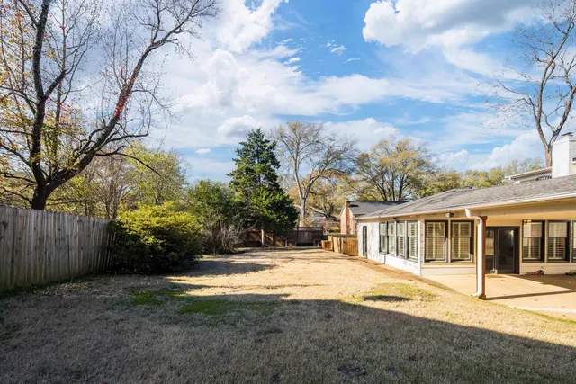 a view of a backyard with wooden fence and a large tree
