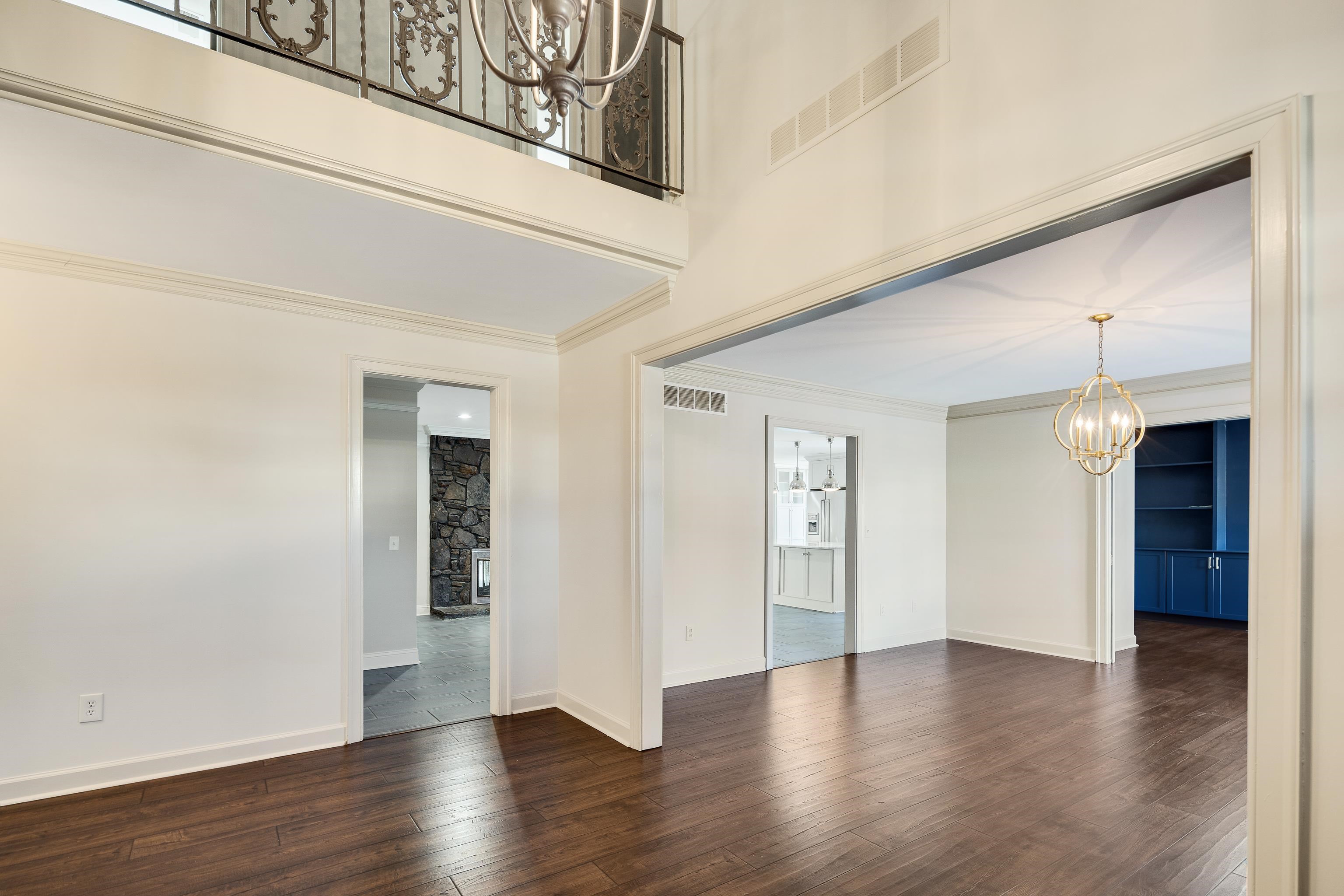 Empty room featuring a chandelier, dark wood finished floors, ornamental molding, and a fireplace