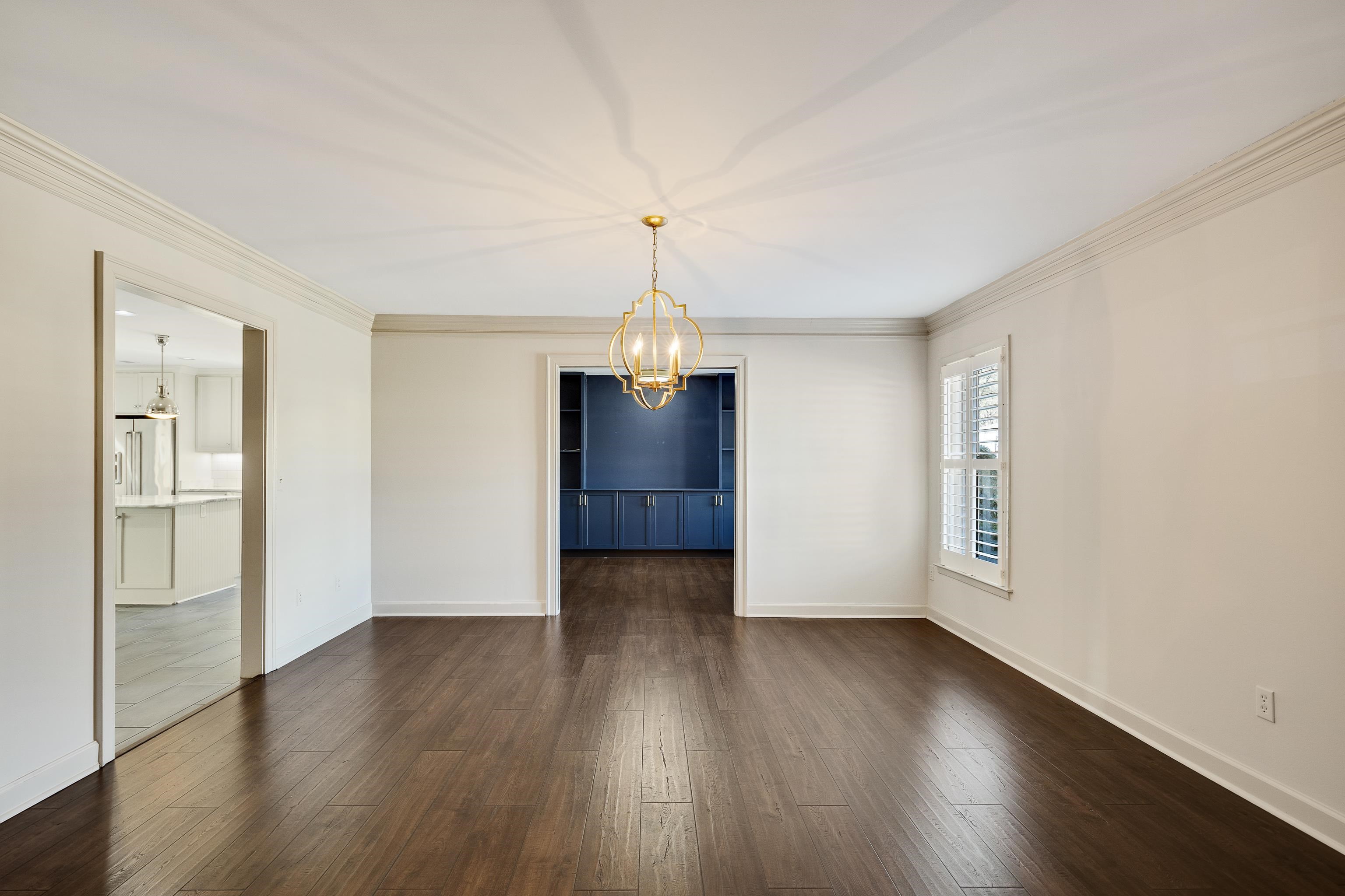 Unfurnished dining area featuring a chandelier, dark wood-type flooring, and crown molding