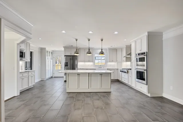 a large white kitchen with stainless steel appliances cabinets a sink and a stove