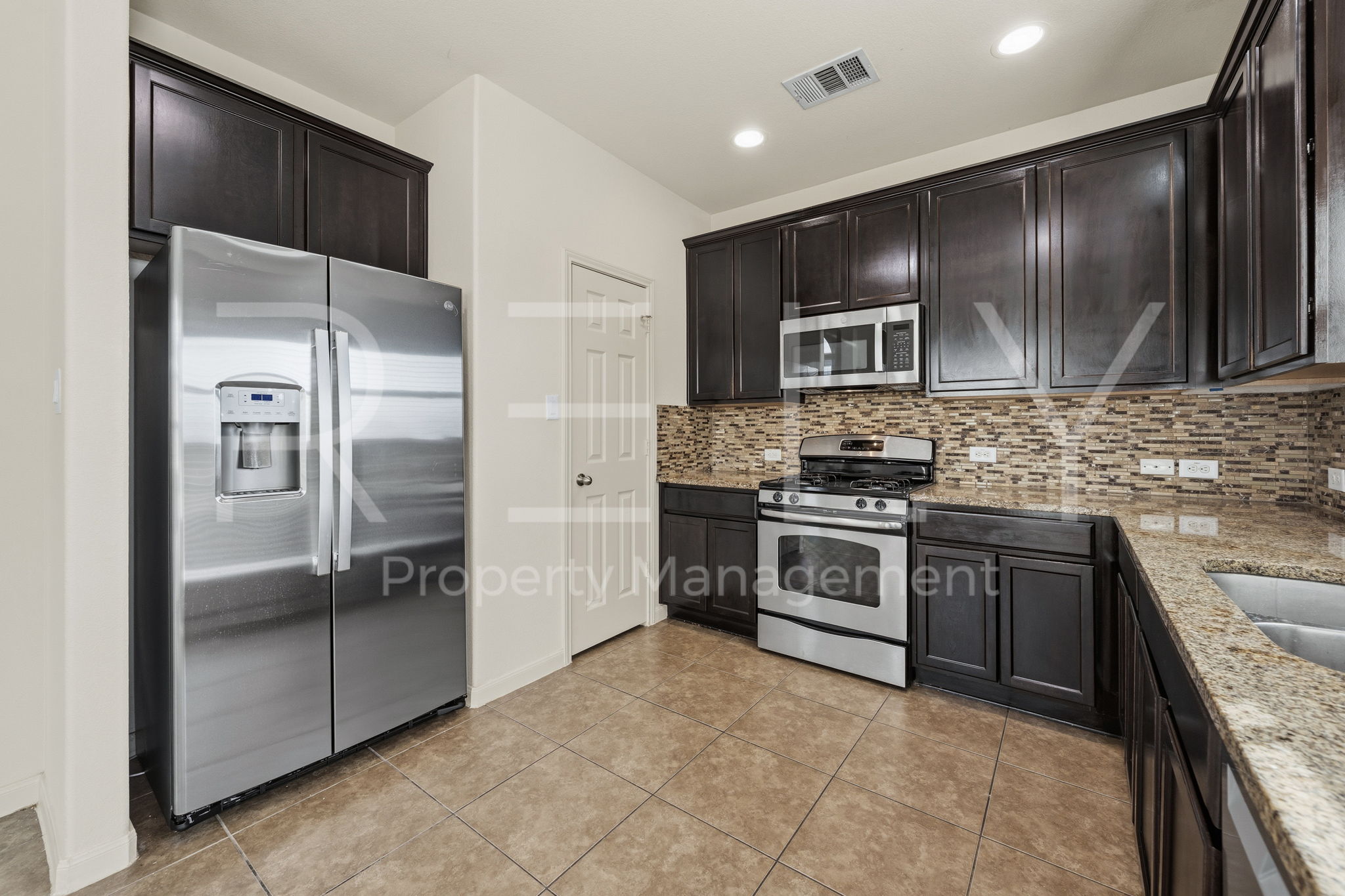 1405 Sunny Meadows Loop Georgetown, TX 78626 - Photo 12 of 40 A well-appointed kitchen features dark wood cabinetry, granite countertops, and modern stainless steel appliances.