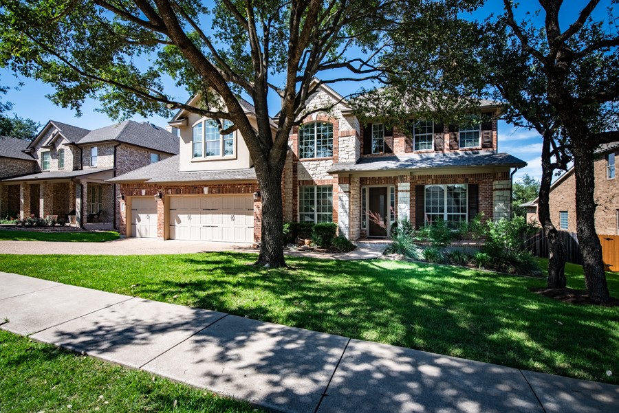 a front view of a house with a garden and trees