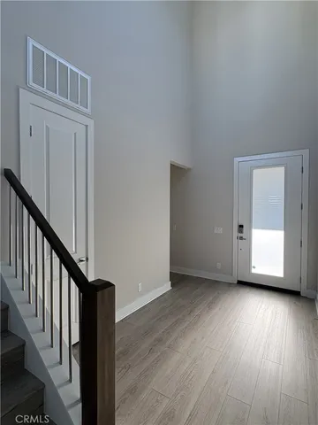 a view of an empty room with wooden floor and stairs