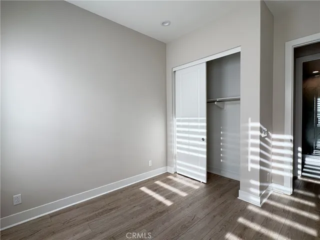 an empty room with wooden floor closet and windows