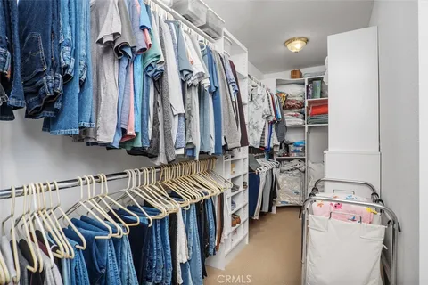 a view of walk in closet with clothes and shoes