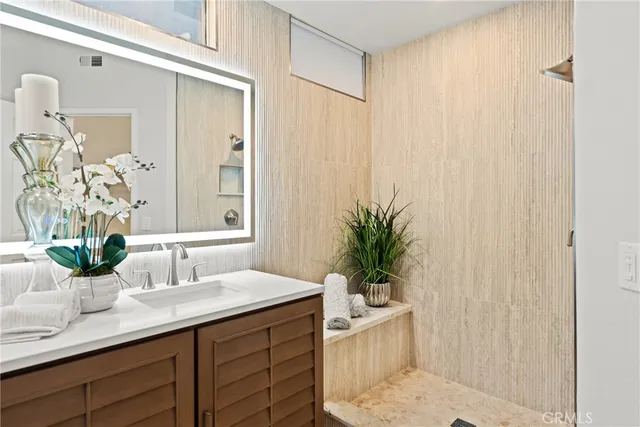 a bathroom with a sink a mirror and a potted plant