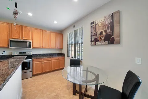 a kitchen with stainless steel appliances granite countertop a stove top oven a sink a dining table and chairs
