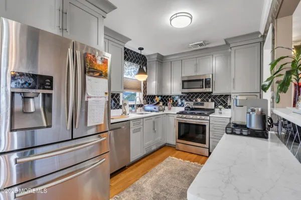 a kitchen with granite countertop a stove a sink and a refrigerator