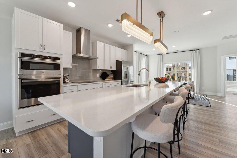 110 Byrum Street, Unit 302 Cary, NC 27511 - Photo 12 of 30 a kitchen with stainless steel appliances kitchen island granite countertop a table chairs in it and wooden floors