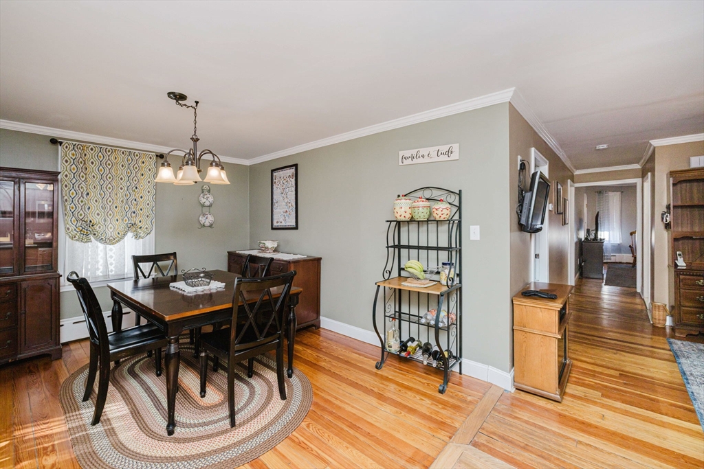 869 Bedford Street Fall River, MA 02723 - Photo 7 of 31 a dining room with wooden floor a chandelier a wooden table and chairs