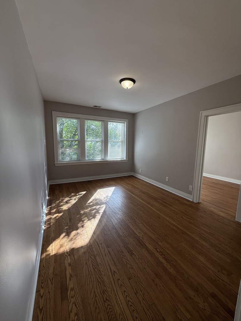 3901 West Division Street, Unit 1150 Chicago, IL 60651 - Photo 3 of 9 a view of an empty room with wooden floor and a window