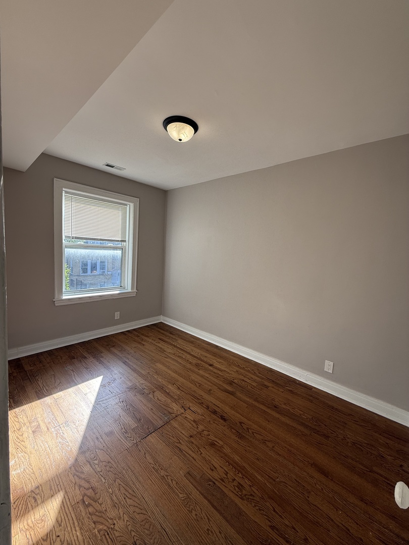 3901 West Division Street, Unit 1150 Chicago, IL 60651 - Photo 4 of 9 an empty room with wooden floor and windows