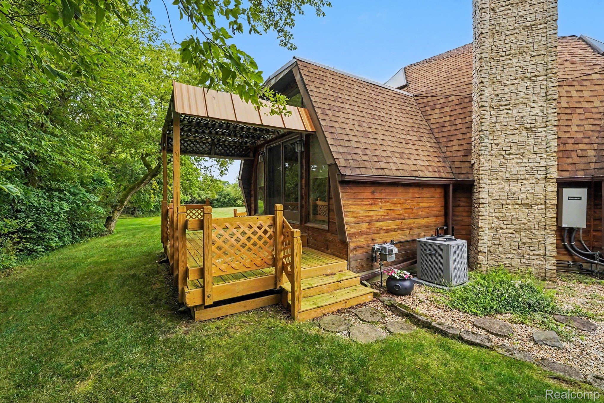 4425 North Henderson Road Davison, MI 48423 - Photo 34 of 43 Wood-sided exterior featuring an A-frame architectural style, a covered wood deck, and a stone chimney
