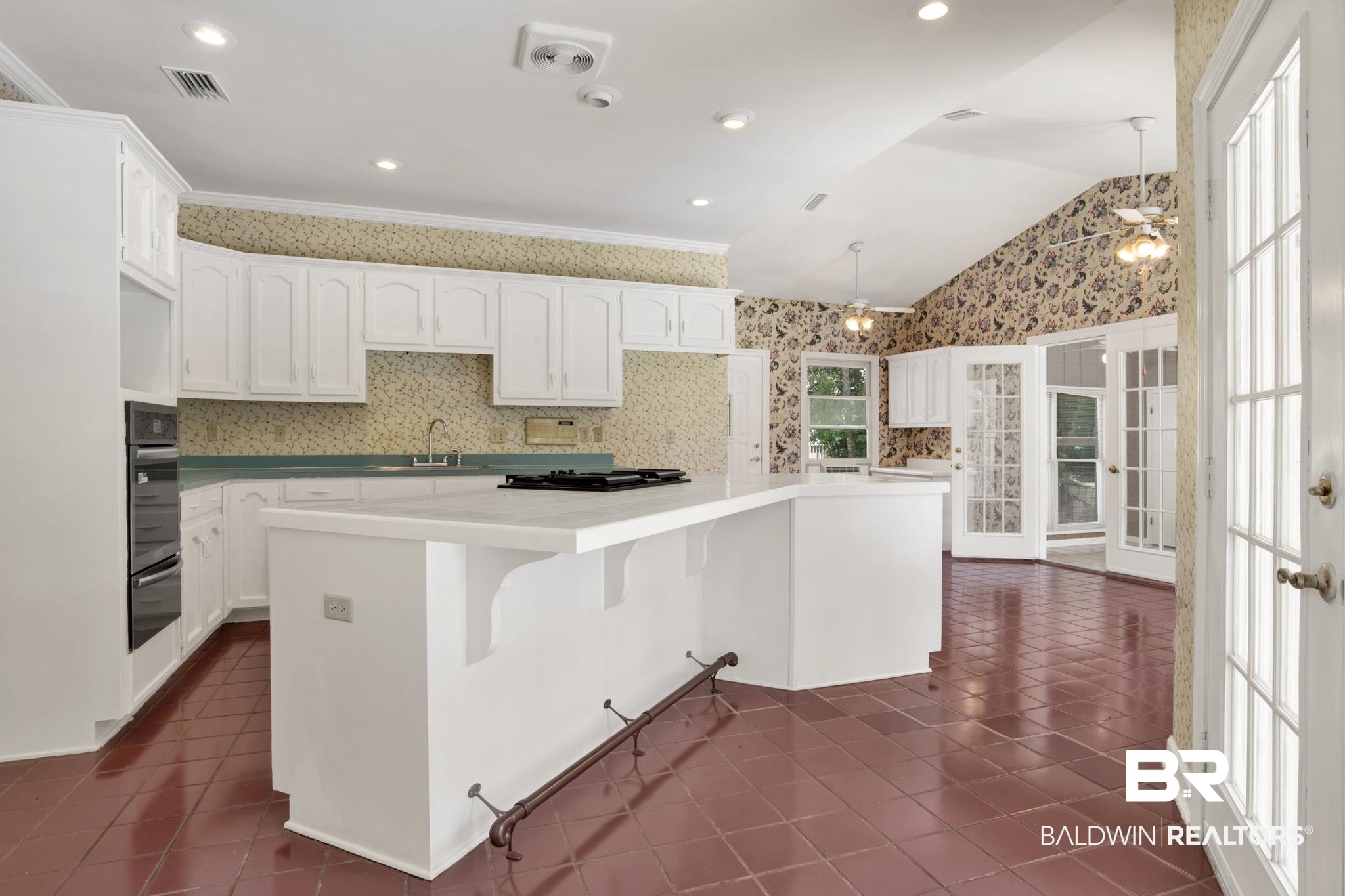 6805 Hunters Court Mobile, AL 36695 - Photo 13 of 37 Kitchen with black oven, a warming drawer, dark tile patterned floors, wallpapered walls, and vaulted ceiling