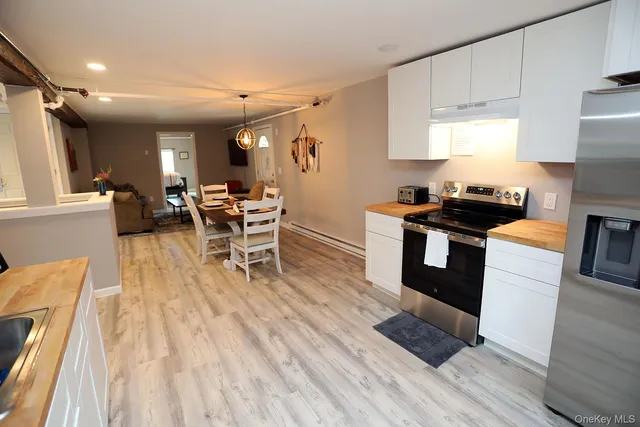 a kitchen with granite countertop a stove top oven a sink dishwasher and white cabinets with wooden floor